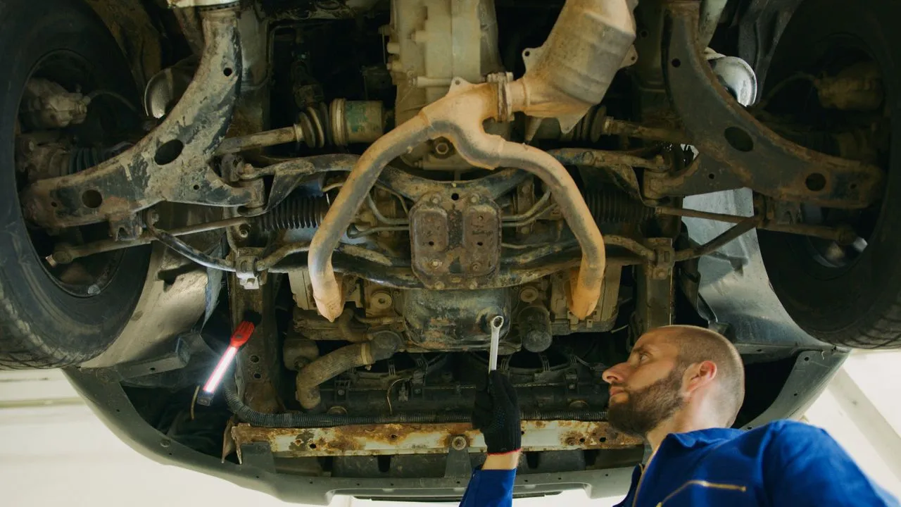 Mehaničar radi na podignutom automobilu u servisu